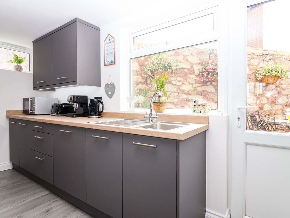 A kitchen with cabinets and appliances at Lilly's Cottage Dawlish
