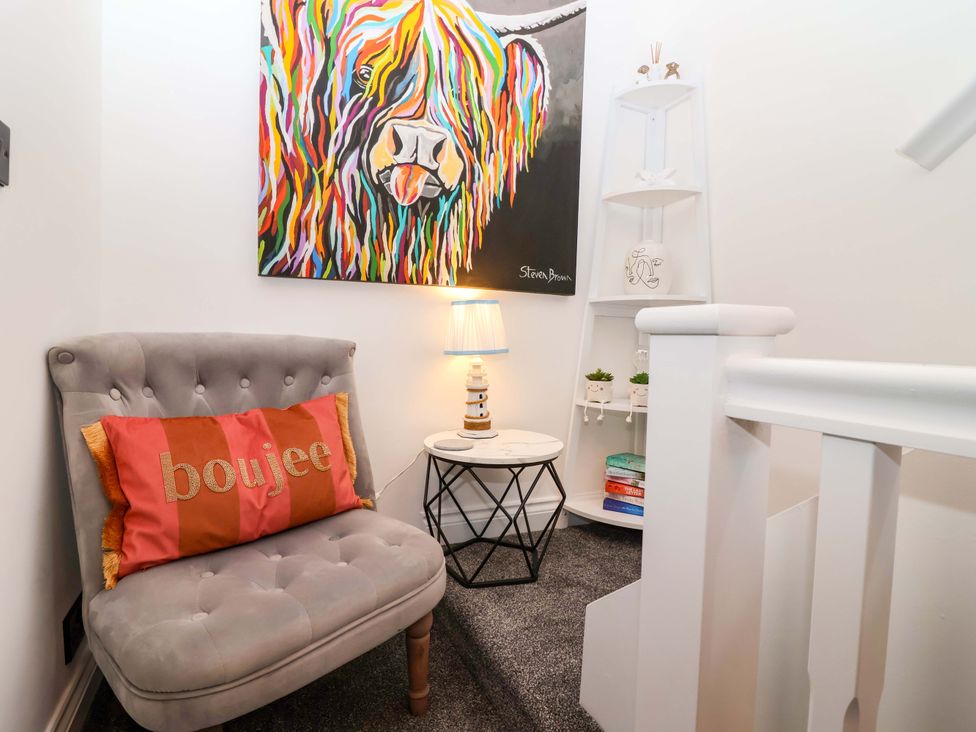 A seating area with a chair and wall art at Lilly's Cottage Dawlish