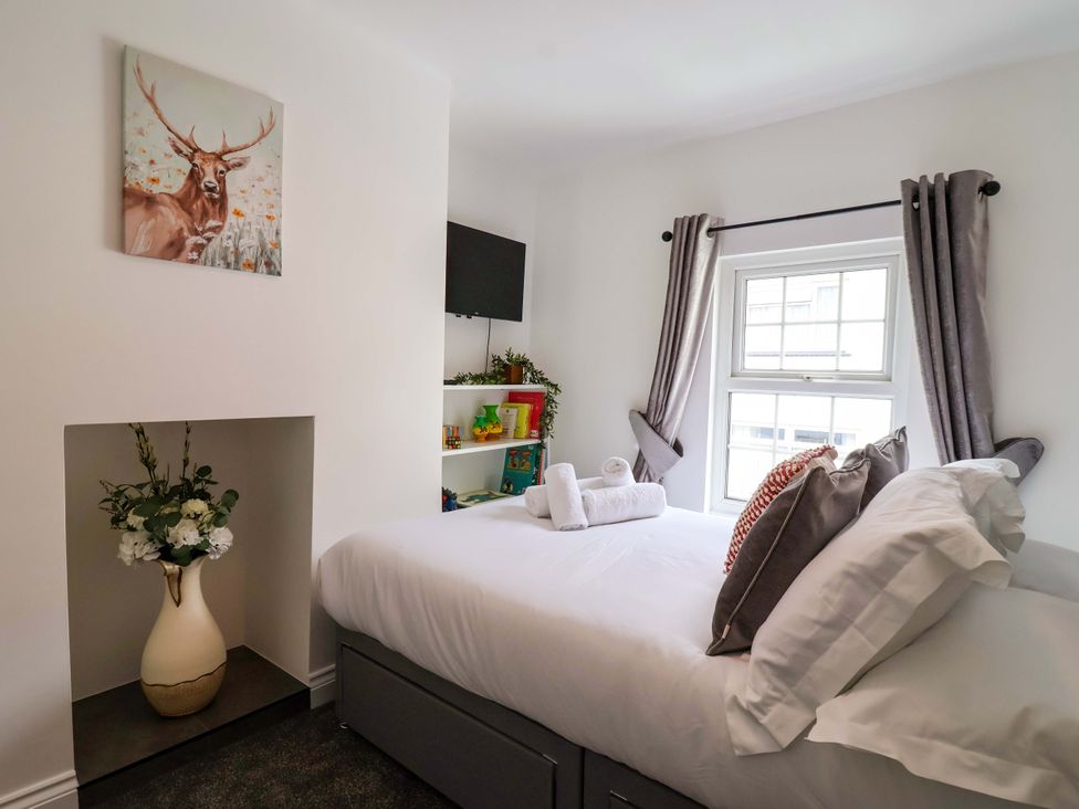 A bedroom with a bed and a vase of flowers at Lilly's Cottage Dawlish