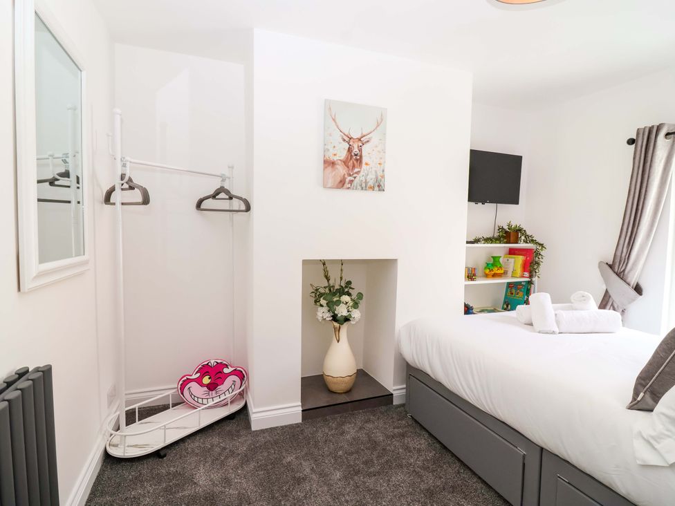A bedroom with a bed and shelf at Lilly's Cottage in Dawlish