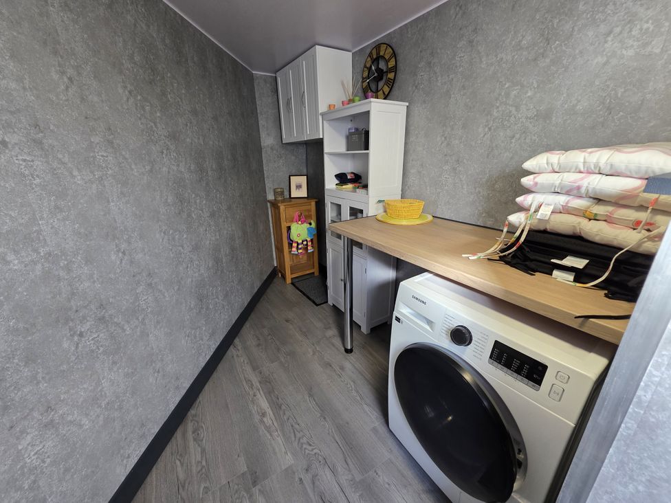 A laundry room with a washing machine and storage at Lilly's Cottage in Dawlish