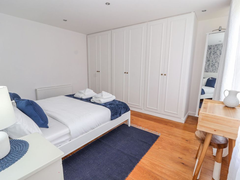 A bedroom with a bed and wardrobe at Mount House in Bryniau near Dyserth