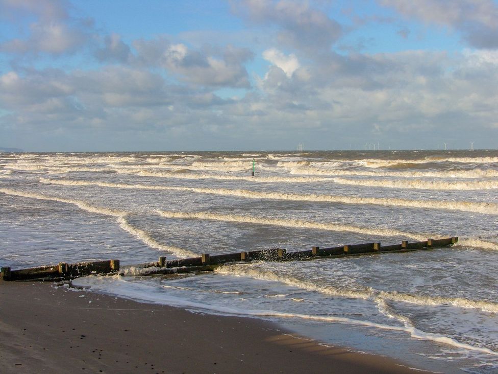 A beach with waves and a wooden groyne at Mount House in Bryniau near Dyserth