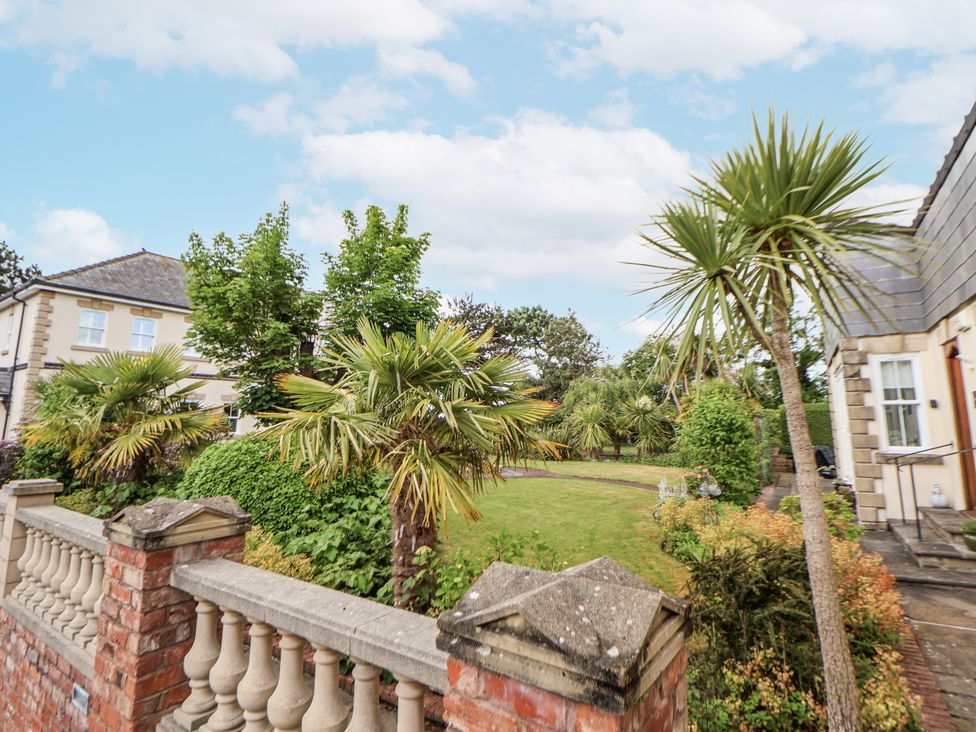 An outdoor area with palm trees and a lawn at Mount House Bryniau near Dyserth
