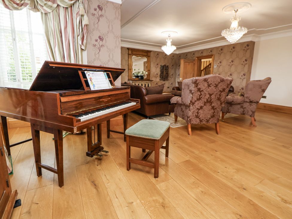 A living room with a piano and seating at Mount House Bryniau near Dyserth