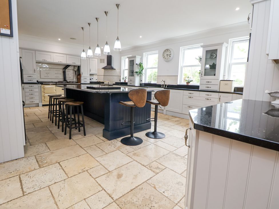 A kitchen with an island and bar stools at Mount House Bryniau near Dyserth