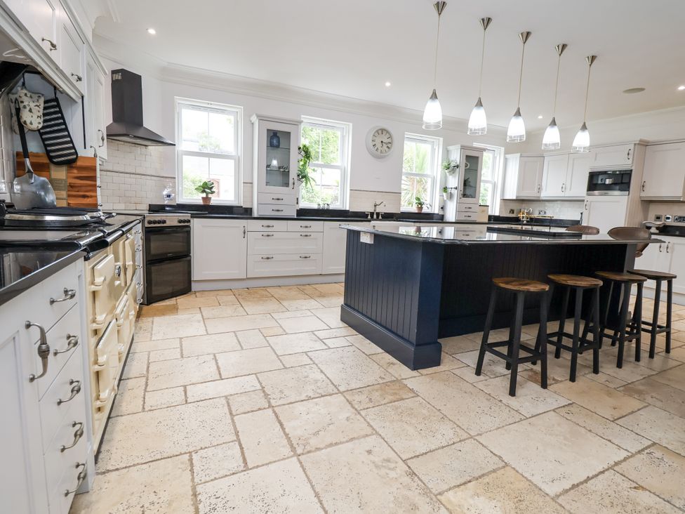 A kitchen with an island and stools at Mount House in Bryniau near Dyserth