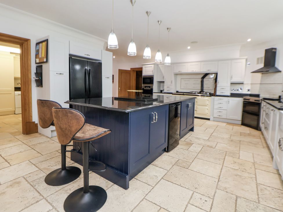 A kitchen with a kitchen island and stools at Mount House Bryniau near Dyserth