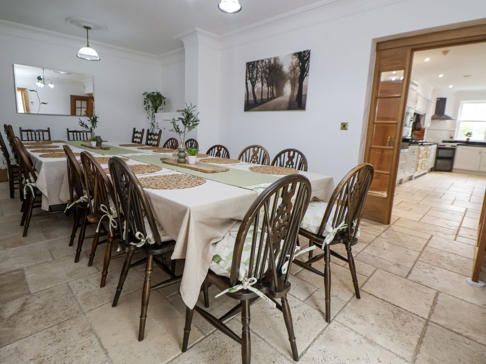 A dining room with a long table and chairs at Mount House Bryniau near Dyserth