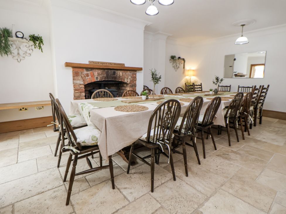 A dining room with a long table and chairs at Mount House Bryniau near Dyserth