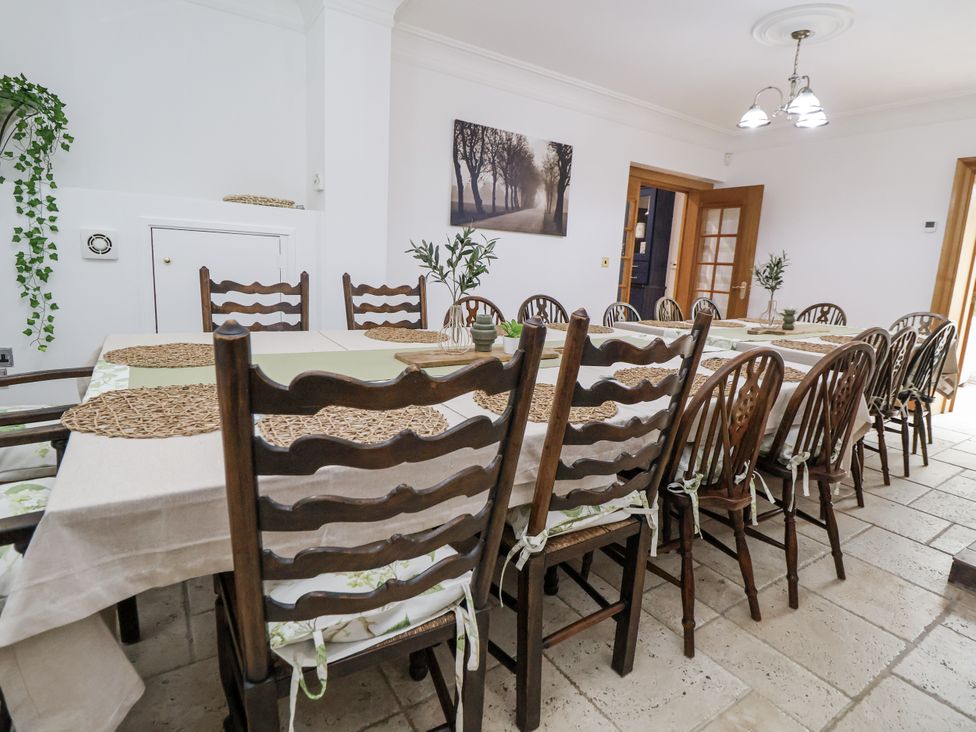 A dining room with a long table and chairs at Mount House in Bryniau near Dyserth