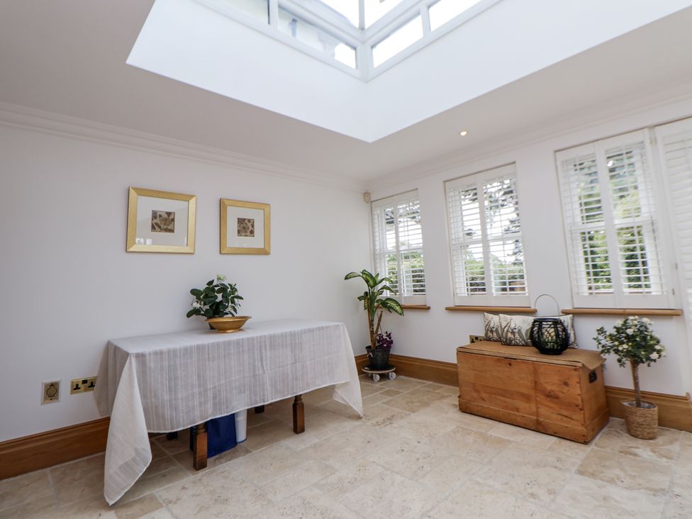 A conservatory with a table and plants at Mount House Bryniau near Dyserth