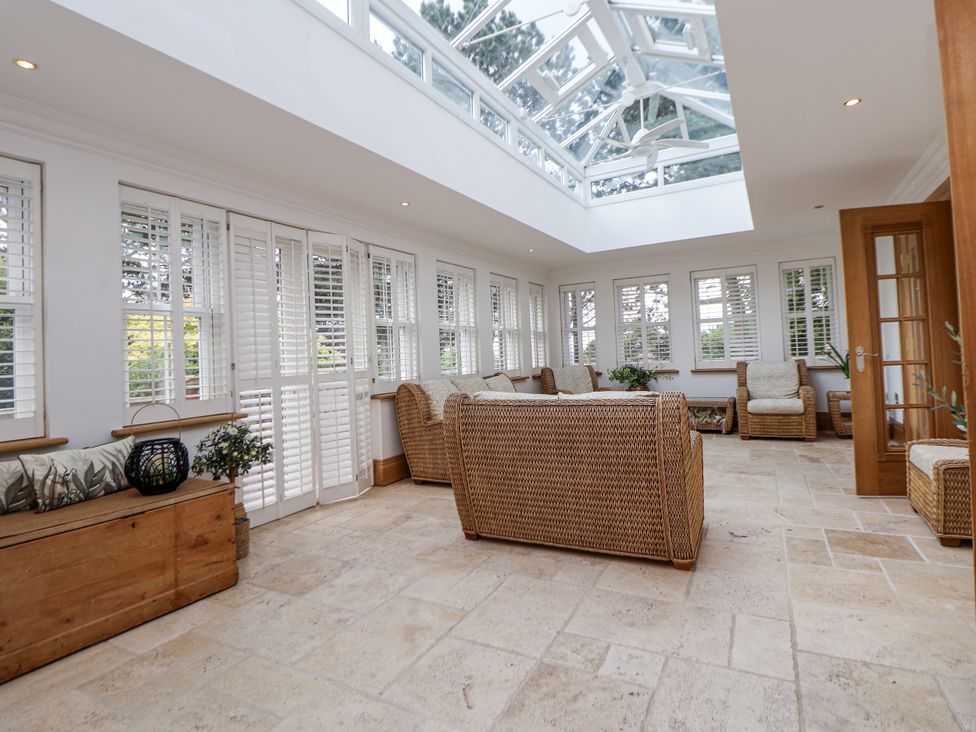 A conservatory with seating and large windows at Mount House Bryniau near Dyserth