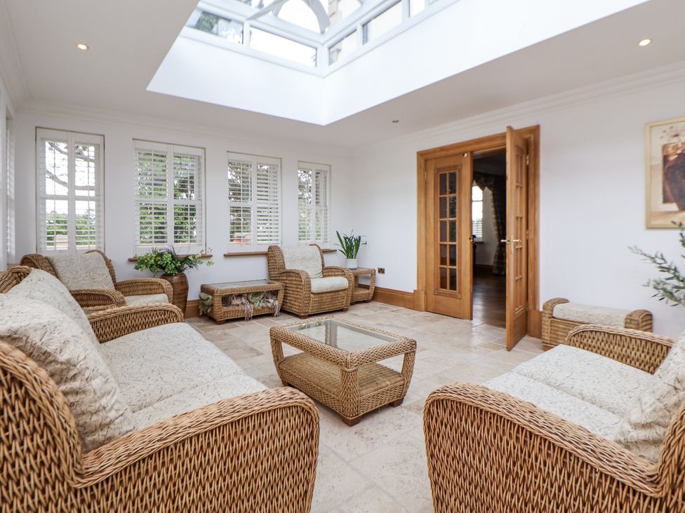 A conservatory with seating and plants at Mount House in Bryniau near Dyserth