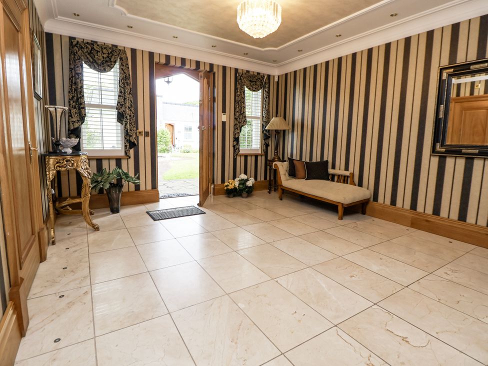 A hallway with a sofa, table, and plants at Mount House Bryniau near Dyserth