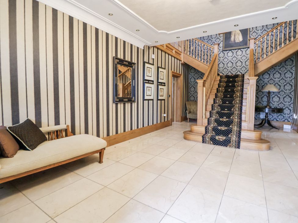 A hallway with a staircase and a sofa at Mount House Bryniau near Dyserth