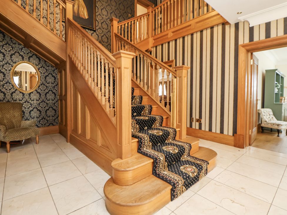 A staircase with a chair and mirror in a hallway at Mount House Bryniau near Dyserth