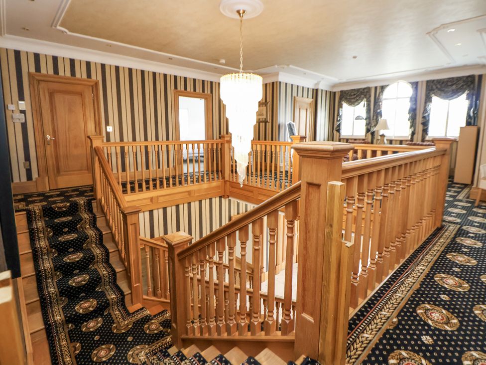 A staircase with wood railing and chandelier at Mount House Bryniau near Dyserth