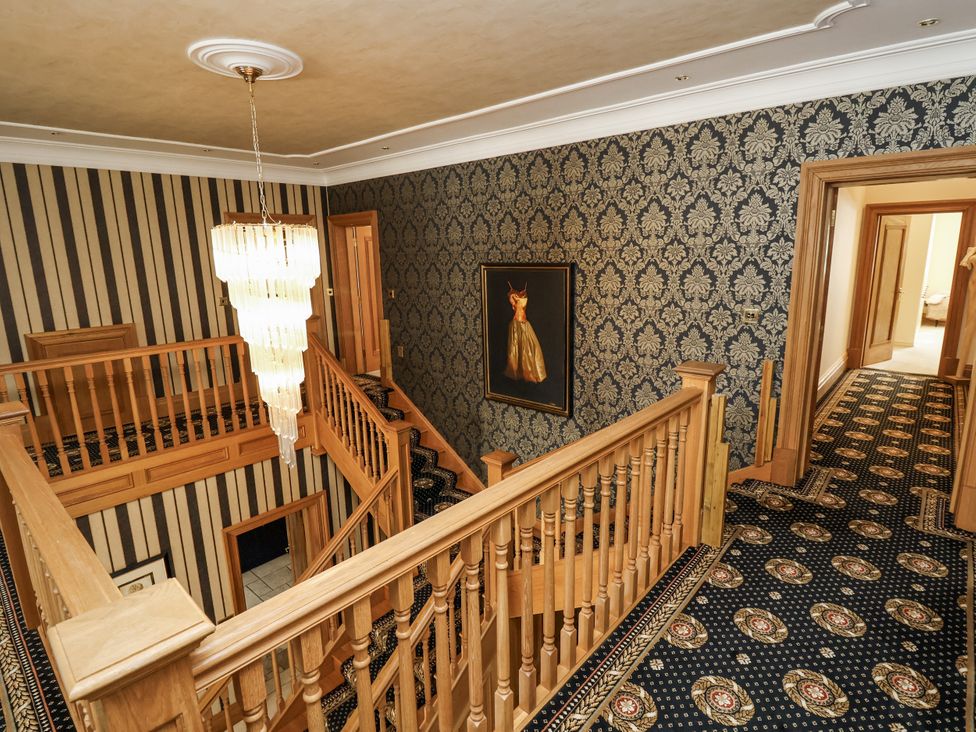 A hallway with a staircase and chandelier at Mount House in Bryniau near Dyserth