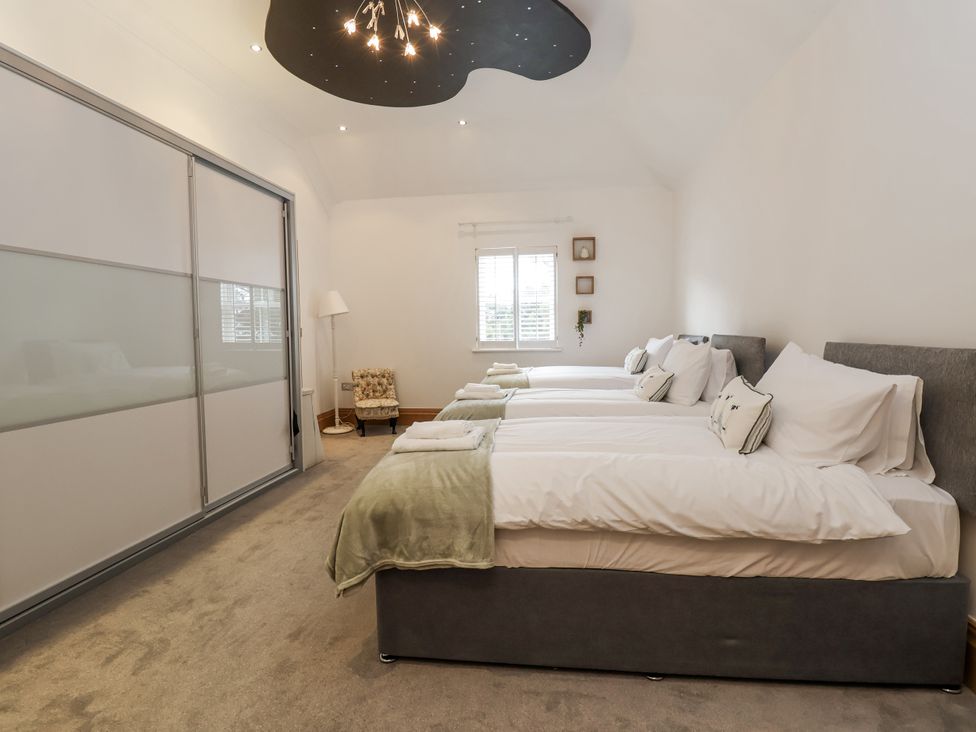 A bedroom with three beds and a wardrobe at Mount House Bryniau near Dyserth