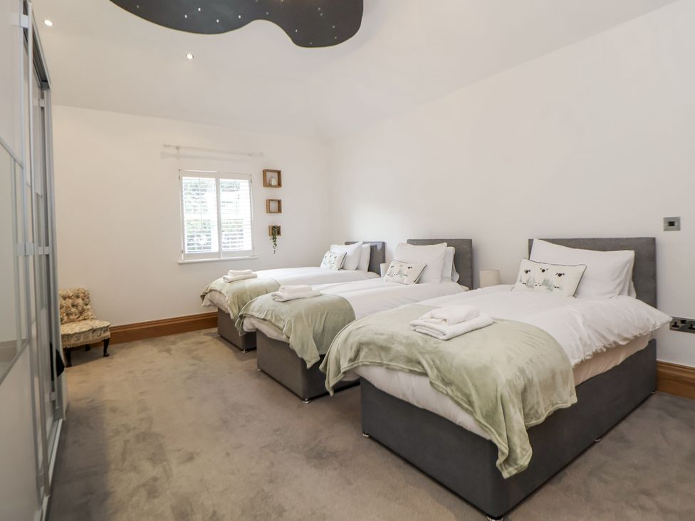 A bedroom with three beds and a chair at Mount House Bryniau near Dyserth