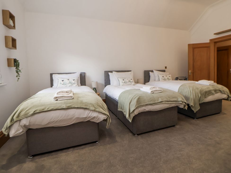 A bedroom with three beds at Mount House Bryniau near Dyserth