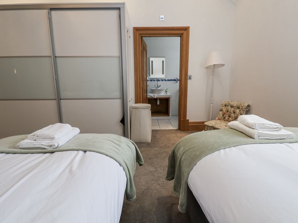 A bedroom with twin beds and a door leading to a bathroom at Mount House in Bryniau near Dyserth
