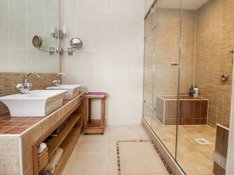 A bathroom with sinks, mirrors, shower and tub at Mount House Bryniau near Dyserth