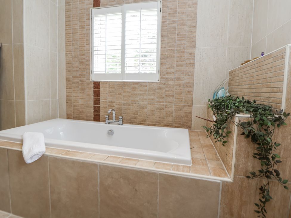 A bathroom with a bathtub and window at Mount House Bryniau near Dyserth