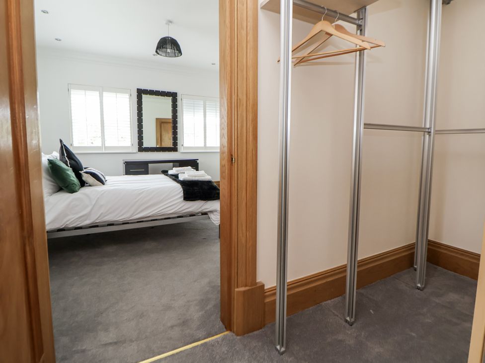A bedroom with a bed and mirror at Mount House in Bryniau near Dyserth