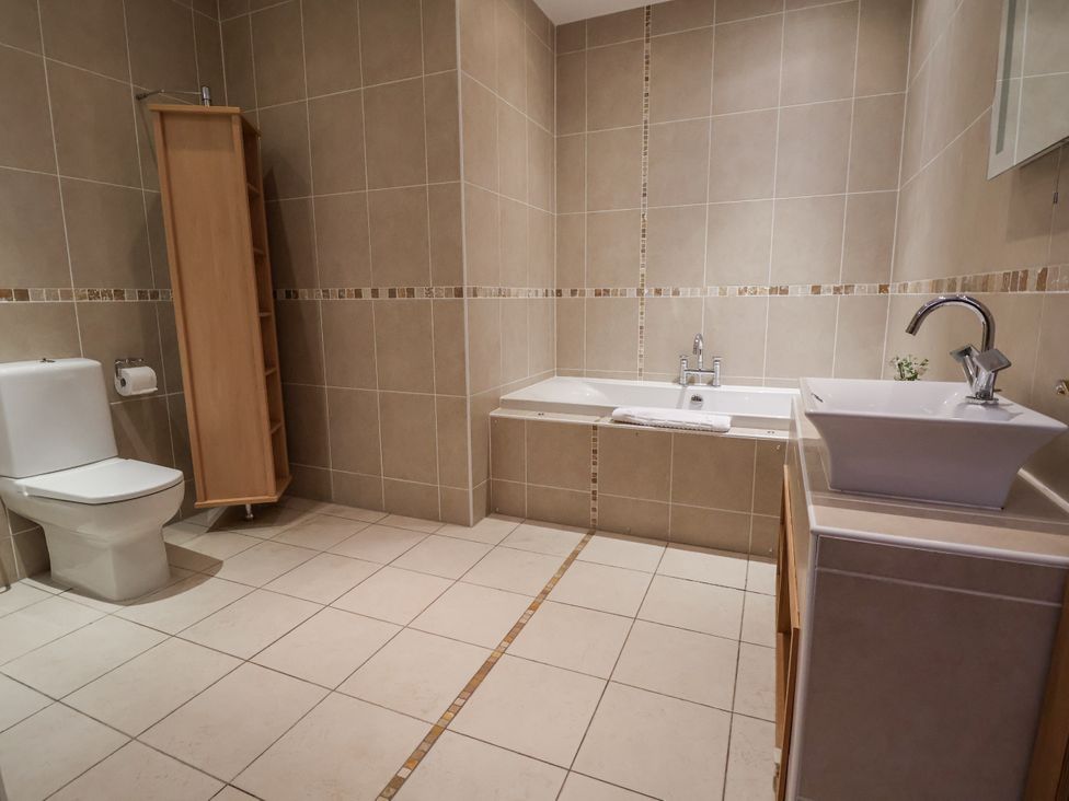 A bathroom with a bathtub, sink, and toilet at Mount House Bryniau near Dyserth