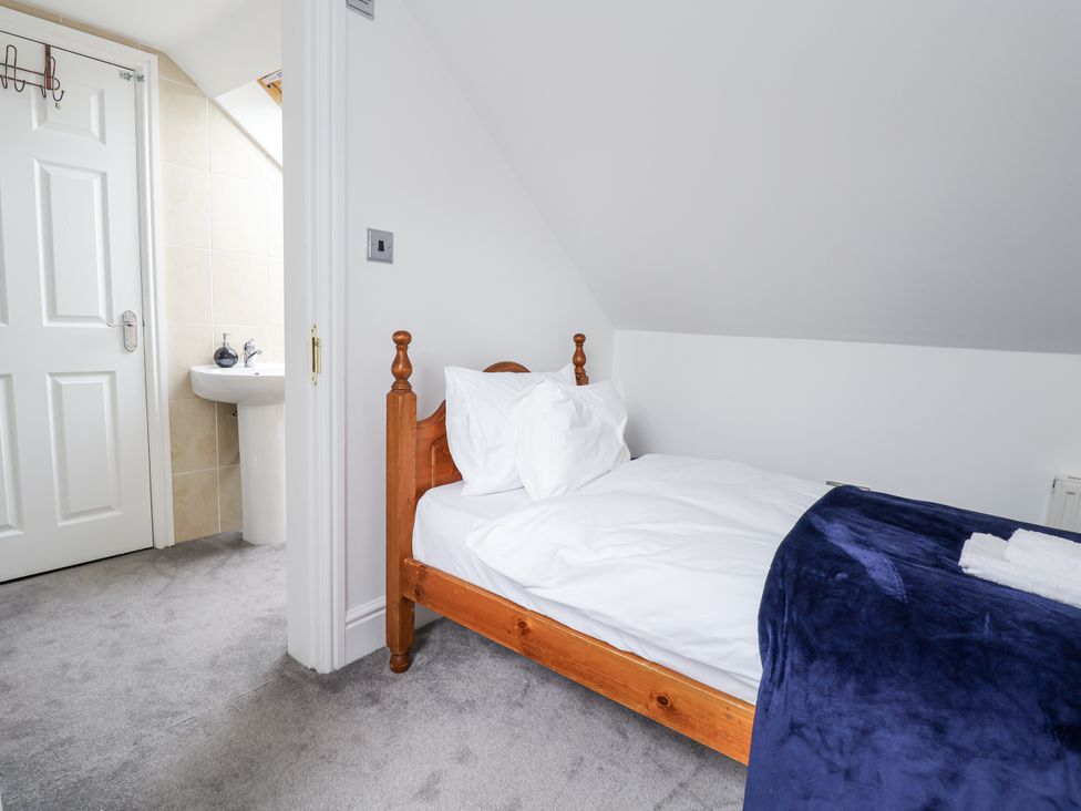 A bedroom with a single bed and a doorway leading to a bathroom at Mount House Bryniau near Dyserth