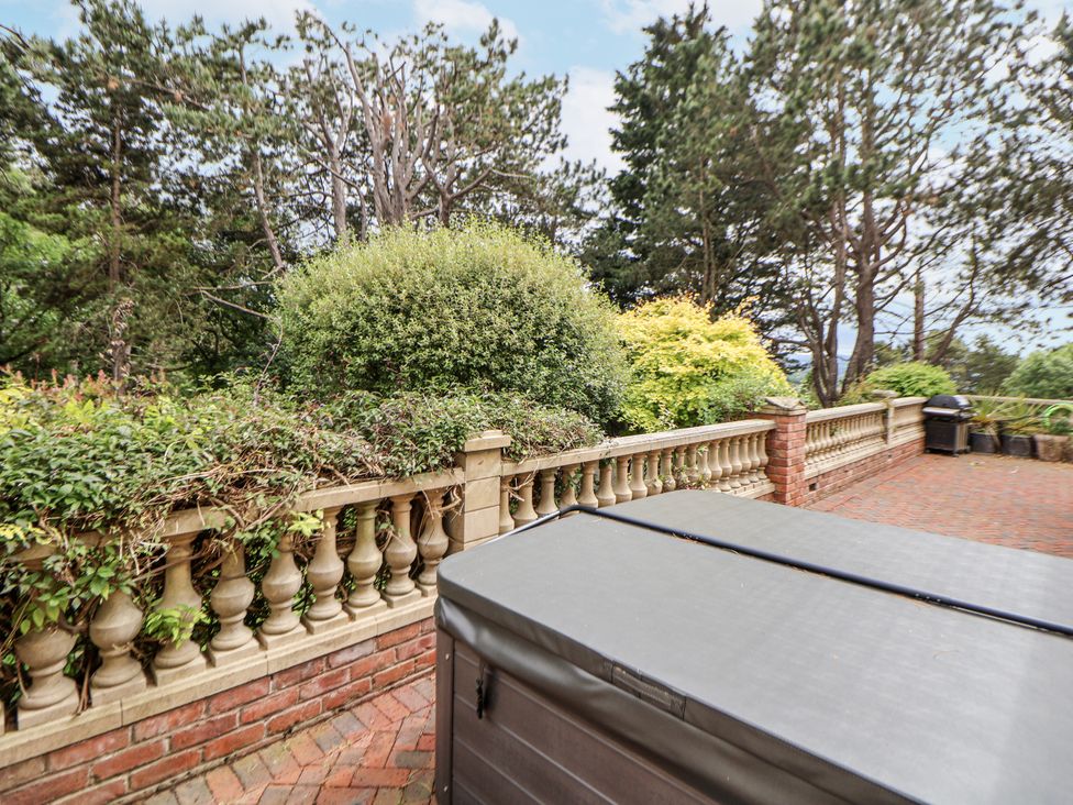 An outdoor area with a hot tub and landscaped hedges at Mount House Bryniau near Dyserth