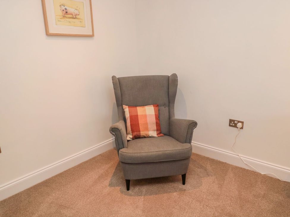 A snug with an armchair and cushion at Harvest Cottage 1 Berwick-upon-Tweed