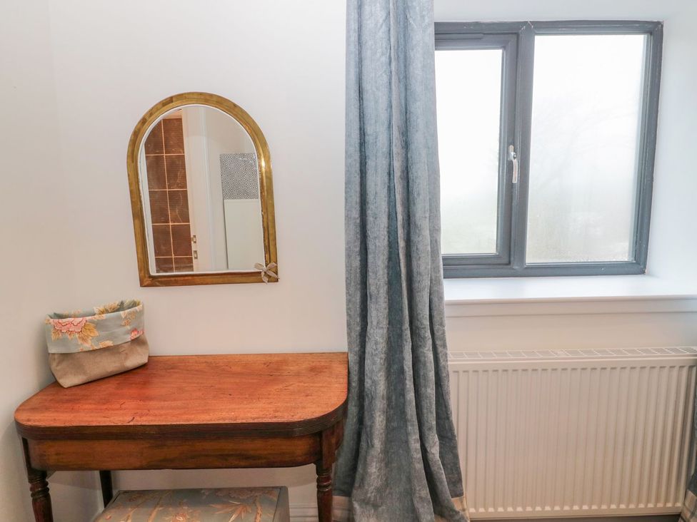 A hallway with a table, mirror, and window at Harvest Cottage 1 Berwick-upon-Tweed