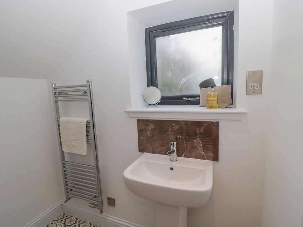 A bathroom with a sink, window, and towel rail at Harvest Cottage 1 in Berwick-upon-Tweed