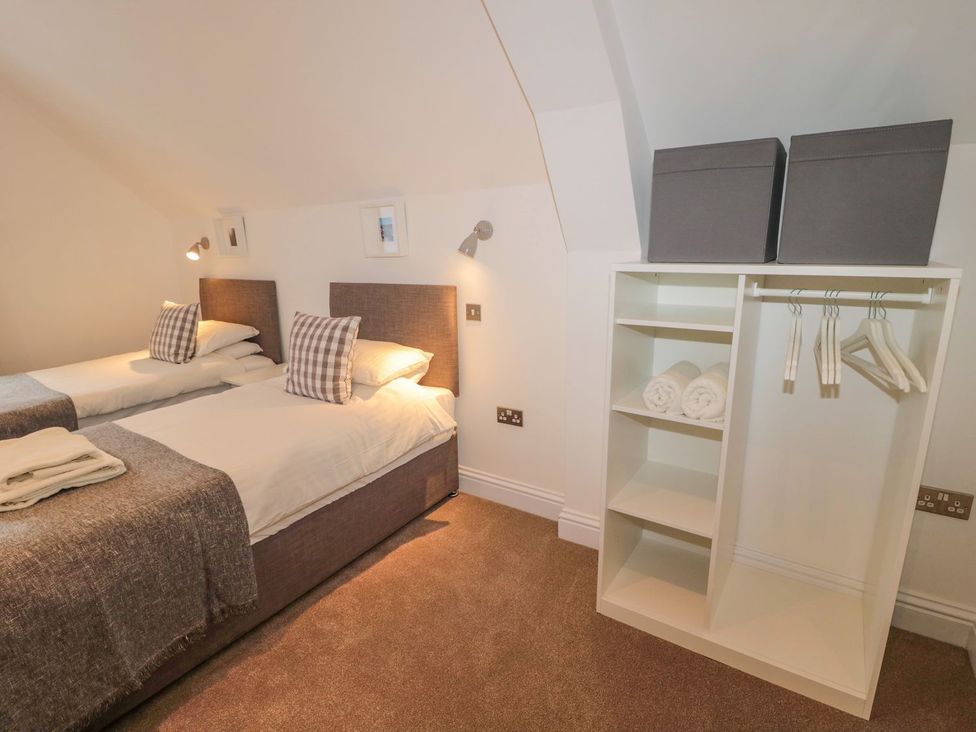 A bedroom with two beds and a storage shelf at Harvest Cottage 1 Berwick-upon-Tweed
