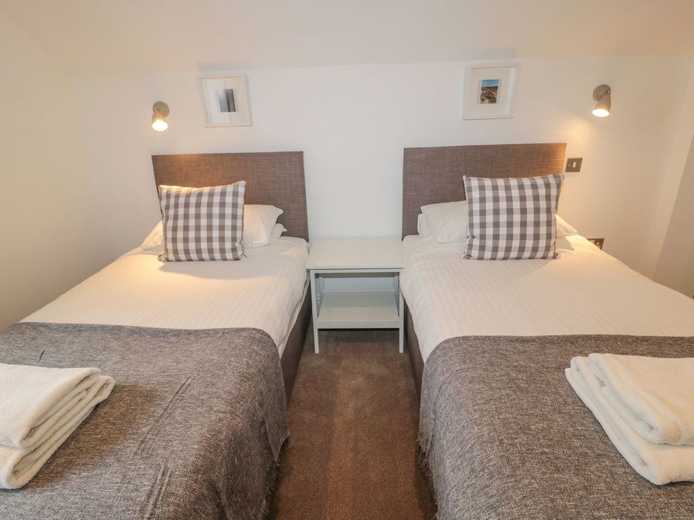 A bedroom with two beds and a bedside table at Harvest Cottage 1 Berwick-upon-Tweed