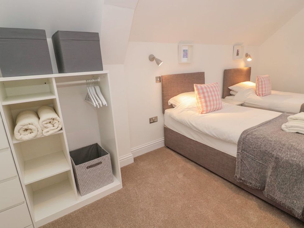 A bedroom with two beds and storage at Harvest Cottage 1 in Berwick-upon-Tweed