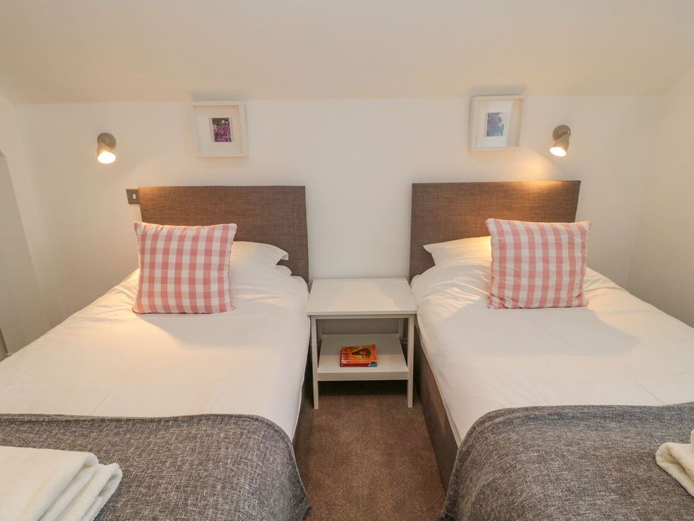 A bedroom with two beds and a nightstand at Harvest Cottage 1 in Berwick-upon-Tweed