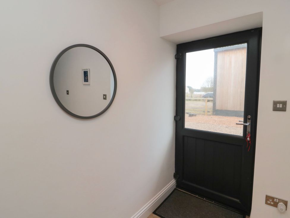 An entryway with a mirror and a door at Harvest Cottage 2 in Berwick-upon-Tweed