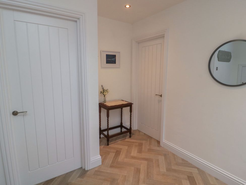 A hallway with a table, door, and mirror at Harvest Cottage 2 in Berwick-upon-Tweed