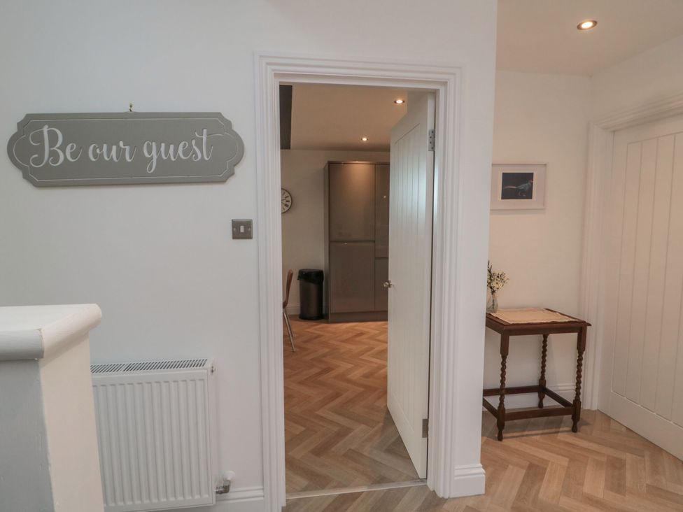 A hallway with a sign and doorway leading to a kitchen at Harvest Cottage 2 Berwick-upon-Tweed