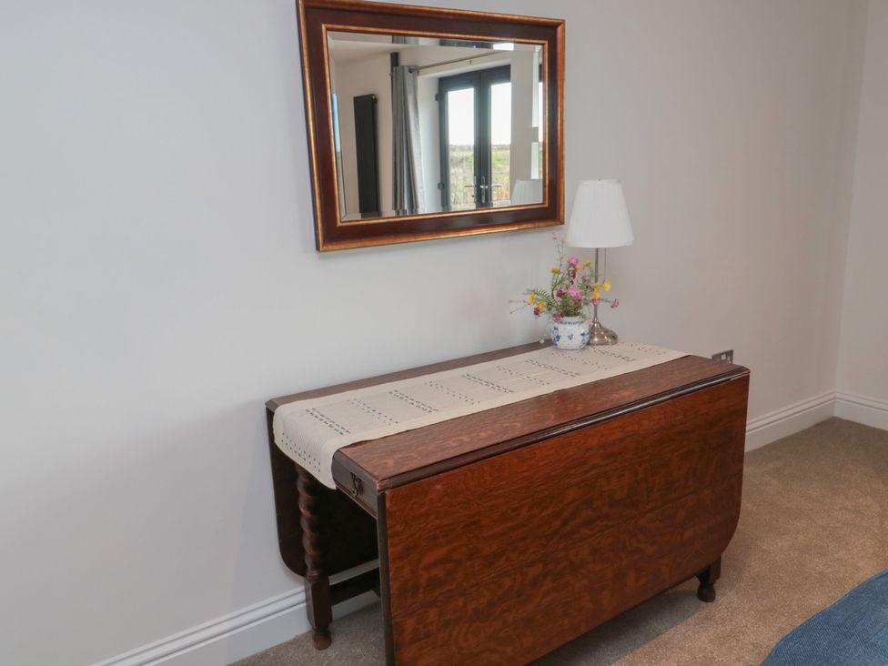 A table with a lamp and flowers under a mirror at Harvest Cottage 2 in Berwick-upon-Tweed