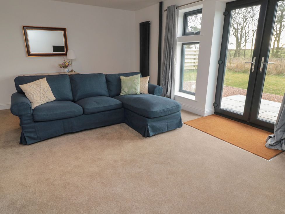 A living room with a sofa and door at Harvest Cottage 2 in Berwick-upon-Tweed