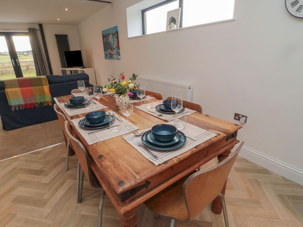 A dining room with a wooden table set for meals at Harvest Cottage 2 Berwick-upon-Tweed