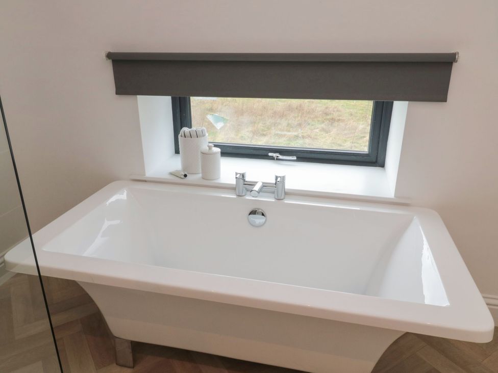 A bathroom with a bathtub and window at Harvest Cottage 2 in Berwick-upon-Tweed