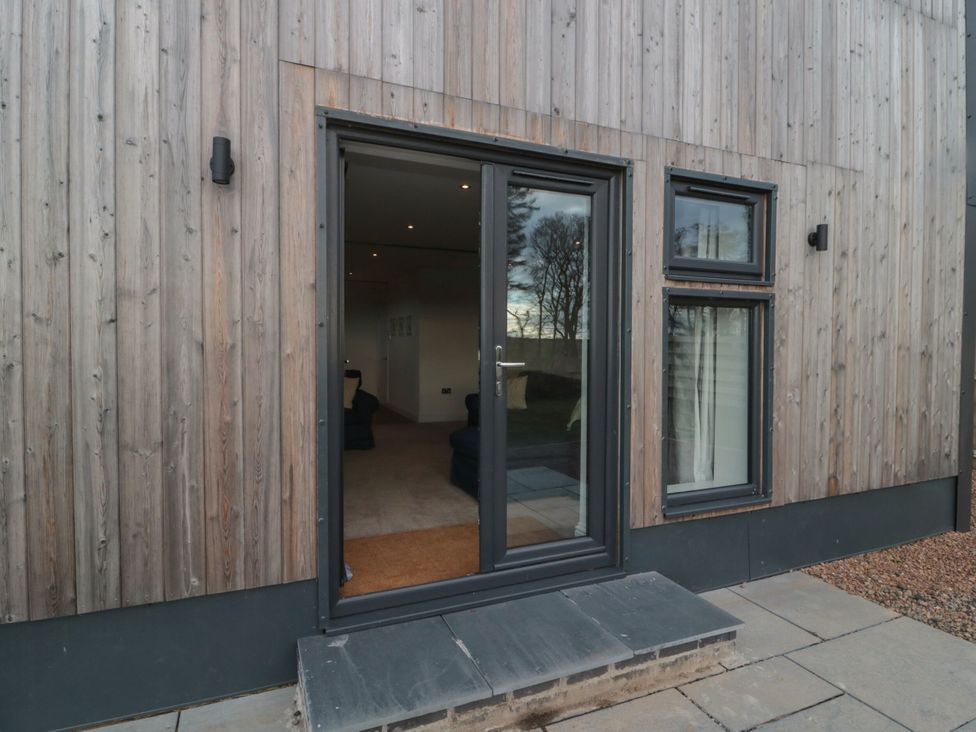 An exterior view of a wooden wall with a glass door and windows at Harvest Cottage 2 Berwick-upon-Tweed