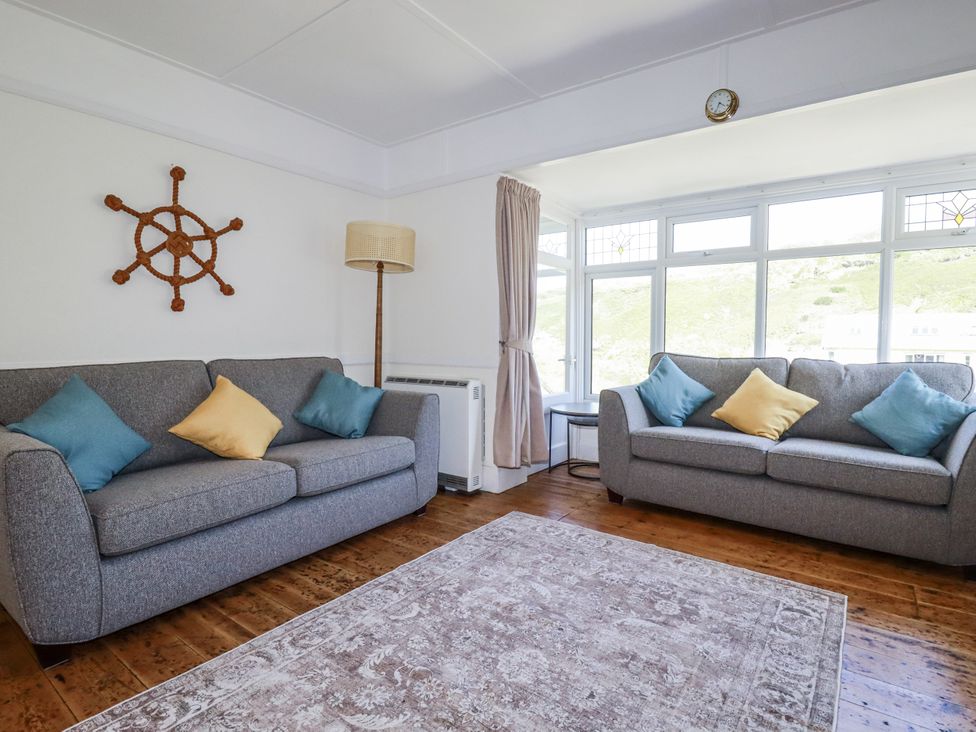A living room with two sofas and a decorative wall piece at Sea Ledge in Tintagel