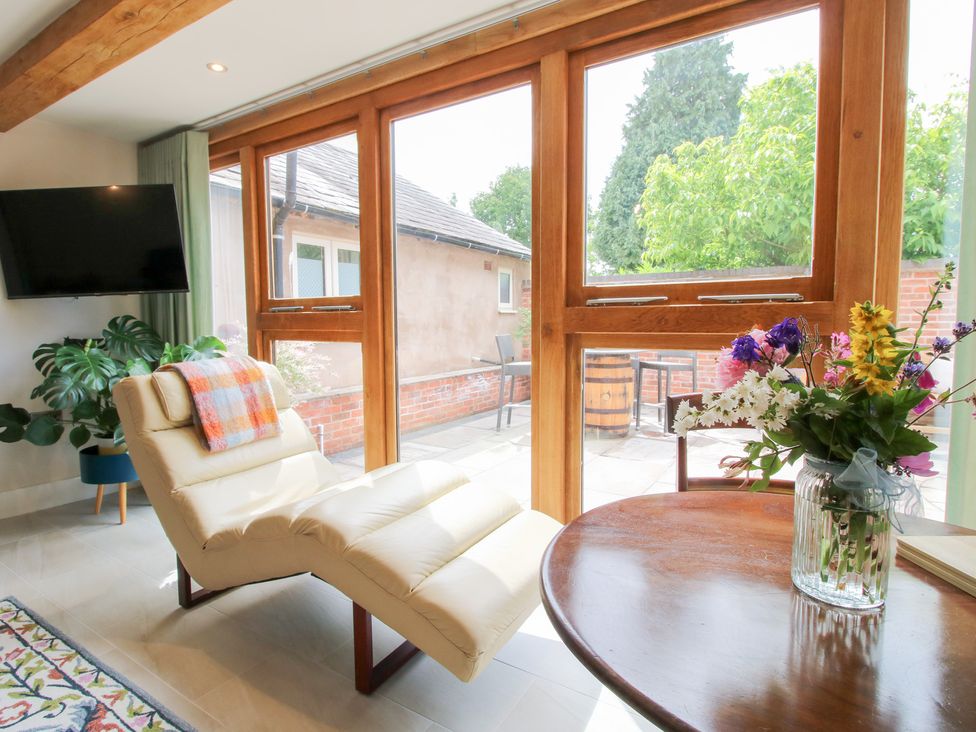A snug with a chaise lounge and flowers on a table at Sylva Cottage Burlton near Cockshutt